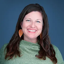 A woman with long hair and big earrings smiling.